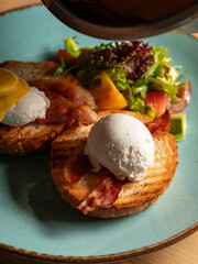 Cooking restaurant breakfast - eggs Benedict with hollandaise cheese sauce, toast and fresh salad by chef hands. Close up, selective focus - 481152755