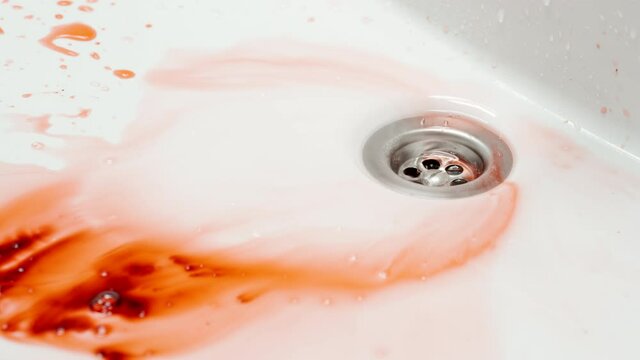 Blood flow down the sink in a stream of water in a bathroom