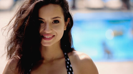 happy brunette woman in swimsuit looking at camera