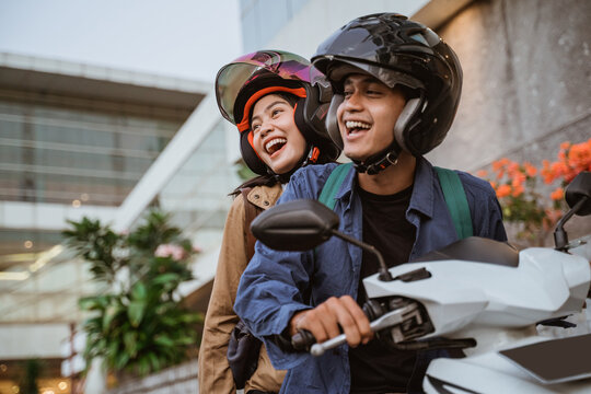 a man and woman laughing while riding a motorcycle