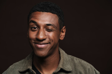 Young black man dressed in shirt smiling and winking at camera
