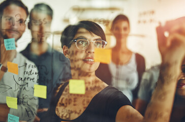 Exploring new possibilities. Cropped shot of a group of young designers using sticky notes during a...