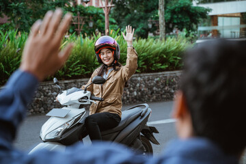 Fototapeta premium Woman wearing helmet riding motorbike waving with someone