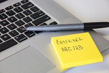 A computer keyboard and a post-it note with a password.