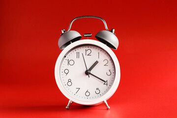 White alarm clock on red background