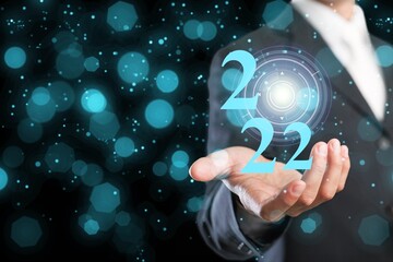 Businessman holding virtual 2022 number with bokeh background for merry Christmas and happy new year concept.