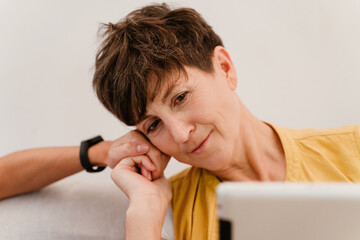 Mature lesbian couple holding hands while using tablet computer