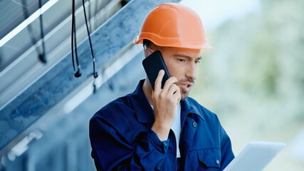 engineer talking on smartphone while holding digital tablet