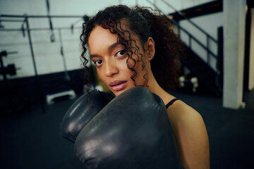 African American female boxer training at the gym with boxing gloves on. Mixed race female holding boxing gloves in air. High quality photo