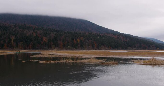 Gloomy weather above pristine intermittent Cerknica lake in Slovenia. Important wetland in karst environment. Autumn or fall season. Static shot, real time