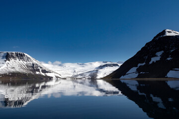 Beautiful mountains with a snow and reflection in the Atlantic ocean. Westfjords, Iceland.