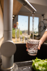 Young woman taking water direct from the tab to drink, showing its's safety to drink tab water and cares for world environment to not wasted of plastic water bottle.Zero waste concept.