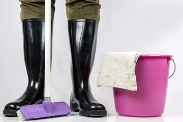 Man in rubber boots with scrubbing brush, mop bucket and cleaning cloth, things for thorough...