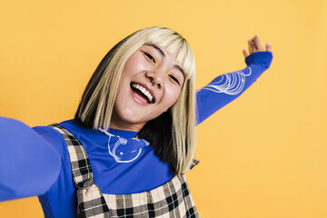 Asian girl with piercing showing copyspace while taking selfie photo