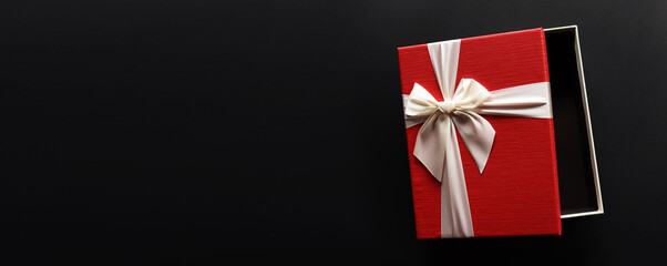 Red gift box  with luxury bow on dark background with copy space, Christmas gift