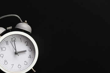 White alarm clock in dark background with copy space. Time concept.