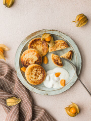 Sweet cheese pancakes on a plate with physalis, top view