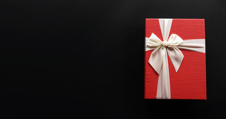 Red gift box  with luxury bow on dark background with copy space, Christmas gift