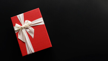 Red gift box  with luxury bow on dark background with copy space, Christmas gift