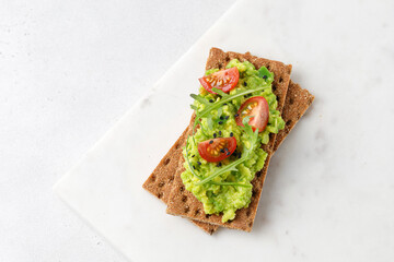 Tasty avocado toasts with  tomatoes cherry and black sesame seeds on white board. Top view....