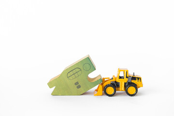 Green wooden house model with front loader truck isolate on white background, clearance sale,...