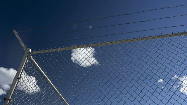 Time lapse of clouds floating past a security fence