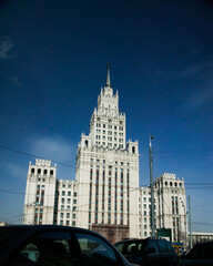 Fototapeta na wymiar The High-rise building of Ministry of Foreign Affairs of Russia in Moscow. Direct sunlight, dark blue sky. One of Stalinist skyscrapers. Dark cars on foreground.