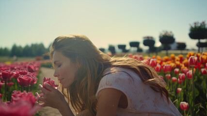 Emotional girl smelling flowers in sunset light. Beautiful woman enjoying flower