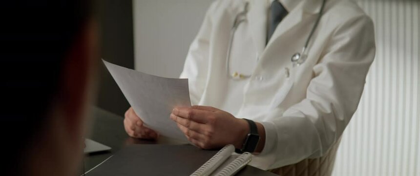 Portrait of stressed supportive Caucasian doctor delivering bad news to his patient during the visit. Shot with 2x anamorphic lens