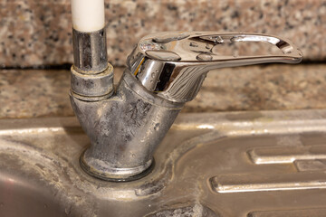 Faucet with limescale. Chlorine and lime stains on the kitchen sink and faucet. The faucet is in selective focus.