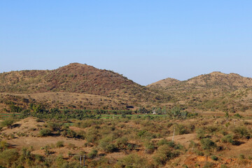 Fototapeta na wymiar This image was captured near Junagadh Gir Forest in winter time at Gir National Park and Sanctuary Gujarat India. clear sky in mountain, yellow grass and green farmland beautiful countryside landscape