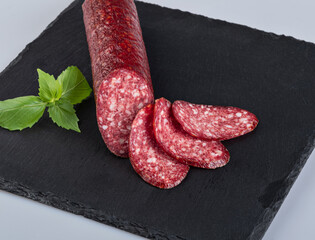 Raw smoked sausage with fresh herbs isolated on a black background