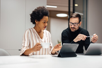 Two focused diverse coworkers, attending a meeting together online.