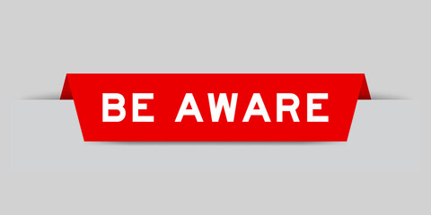 Red color inserted label with word be aware on gray background