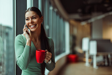 Confident caucasian employee, holding a red cup, talking to a client.