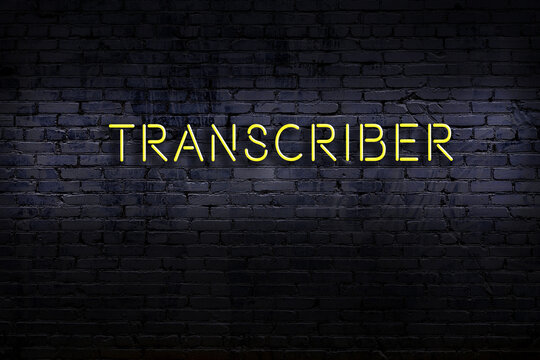 Neon sign. Word transcriber against brick wall. Night view