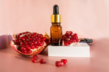Composition with natural cosmetic oil and pomegranate on light background