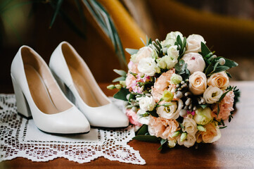 Wedding accessory bride. Stylish lacquered white shoes and bouquet of flowers on wooden background.