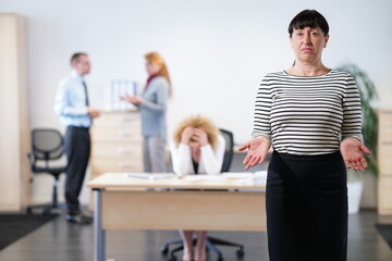 3 Büroangestellte streiten im Hintergrund, während die Chefin ratlos ist
