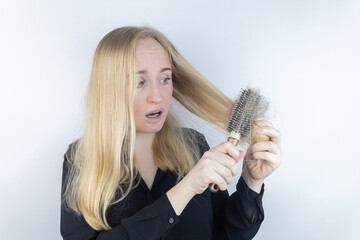 Close-up of a girl whose hair is falling out. There is a large tuft of tangled curls on the comb....