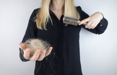 Close-up of a girl whose hair is falling out. There is a large tuft of tangled curls on the comb....