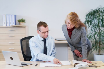 Chef erklärt der Sekretärin etwas in einer Akte