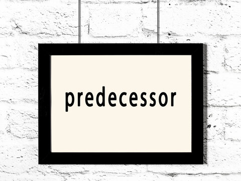 Black frame hanging on white brick wall with inscription predecessor
