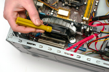 a master with a screwdriver in his hand repairs an old dusty computer