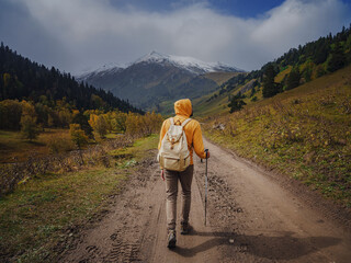 Man hikes mountains with travel backpack. Wandering lifestyle, adventure concept autumn vacation outdoors, alone in wild. Travel to North Caucasus, Arkhyz, Russia. road to Dukkinsky lakes