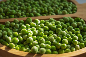frozen frosty green peas on wooden plate closeup