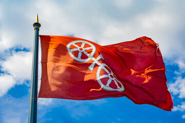 Great close-up view of the flag of Mainz, the capital and largest city of Rhineland-Palatinate, Germany. It consists of a silver wheel, the so called Mainzer Rad, with six spokes on a red background. - obrazy, fototapety, plakaty
