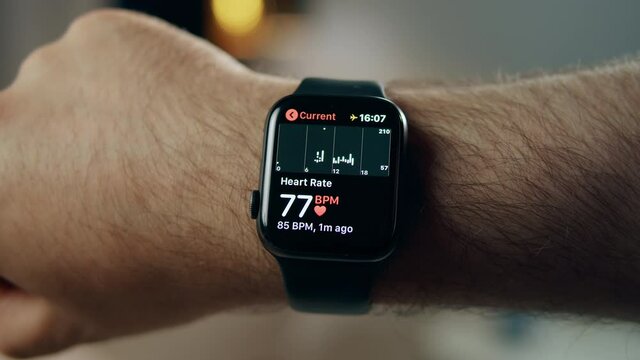 Man using smartwatch close-up. Male person wearing fitness bracelet, checking heart rate, measuring pulse on wrist.