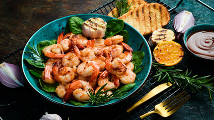 Grilled shrimp with spices and hot chili on a plate. Side view. Seafood. On a stone background.