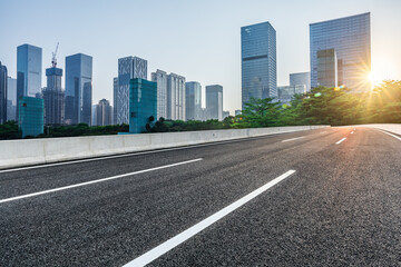 Asphalt road and city skyline with modern commercial office buildings in Shenzhen at sunrise, China.